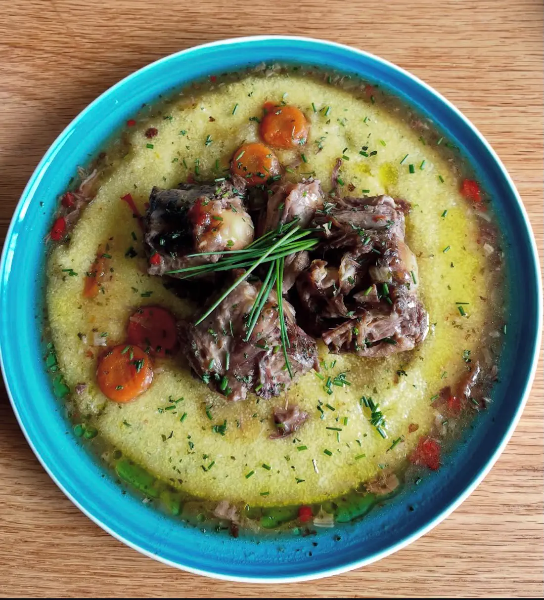 Gestoofd rundvlees op polenta met wortel, erwtjes en bieslook